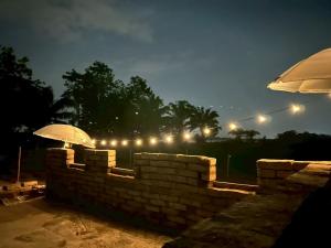 a brick wall with two umbrellas and a brick wall with lights at Jantawan Hostel in Ban Khlong Chet (2)