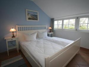 a bedroom with a large white bed with two windows at Apartment Tohus - Wigbold by Interhome in Middelhagen