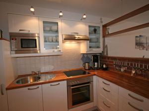 a kitchen with white cabinets and a sink and a microwave at Apartment Tohus - Wigbold by Interhome in Middelhagen