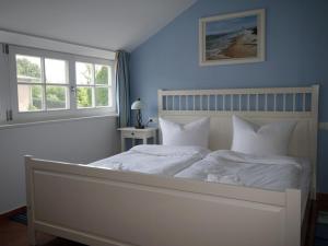 a bedroom with a white bed with two windows at Apartment Tohus - Wigbold by Interhome in Middelhagen +27 photos
