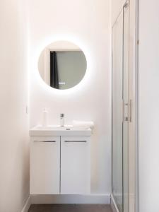 a white bathroom with a sink and a mirror at Hôtel des Cousines Capucine Apartment in Nancy