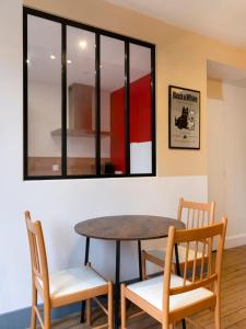 a table and chairs in a room with a window at Hôtel des Cousines Capucine Apartment in Nancy