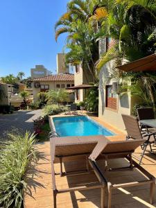 a pool with two chairs and a table next to a house at Hotel Vila Serrana in Sete Lagoas