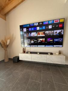 a large flat screen tv on a wall at Appartement Vue Montagne Vignoble Cosy Valais in Chamoson +16 photos
