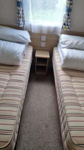 two beds in a small room with a small table at 87 Mountain View, Hafan Y Mor in Afon Wen Junction