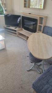 a living room with a table and a tv at 87 Mountain View, Hafan Y Mor in Afon Wen Junction