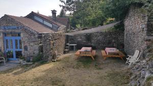a stone building with tables and chairs in front of it at La Butinerie in Prévenchères