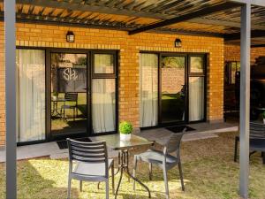 a patio with a table and chairs and windows at Sage Haven Guesthouse in Modimolle
