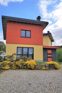 a red and yellow house with flowers in front of it at Holiday Home mit Wallbox by Interhome in Eibenstock