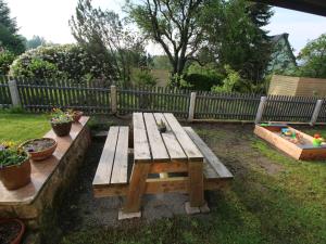 a wooden picnic table in a yard with potted plants at Holiday Home mit Wallbox by Interhome in Eibenstock +24 photos