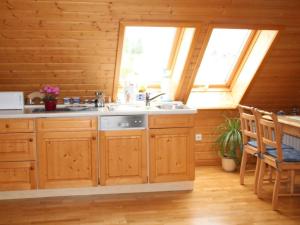 a kitchen with wooden cabinets and a sink and two windows at Apartment FeWo Panorama by Interhome in Rauenstein