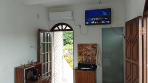 a room with an open door with a television on the wall at Casa Rosa da Ilha - Suíte com Ar-condicionado e Jardim Amplo in Vera Cruz de Itaparica