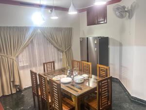 a dining room table with chairs and a kitchen at Bloom Fort Villa in Kannur