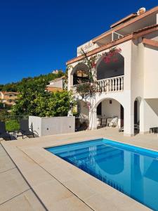 a villa with a swimming pool in front of a house at Bella Vista Dalmatien in Čelina
