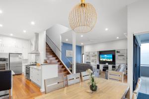 a kitchen and living room with a dining room table and a staircase at Coffs Jetty Beach House in Coffs Harbour