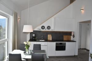 una cucina con mobili bianchi e un tavolo con sedie di Ferienhaus Marianne a St. Wolfgang