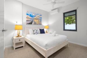a white bedroom with a bed and a window at Coffs Jetty Beach House in Coffs Harbour