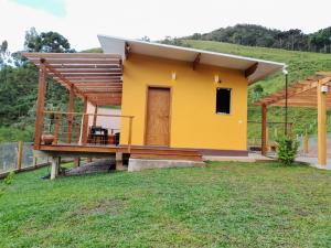 a small yellow house with a wooden deck at Chalé Topázio Gonçalves in Gonçalves