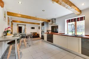 a kitchen with white cabinets and a table with stools at 4 Bed in High Peak oc-dcchb in Chinley
