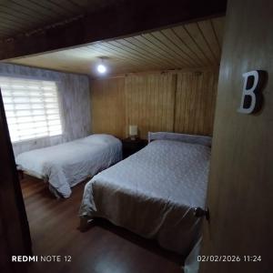 a bedroom with two beds and a window at HOSTAL CARHUELLO in Pucón