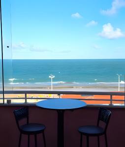 a table with two chairs and a view of the ocean at Apartamento Cantinho do Mar in Natal