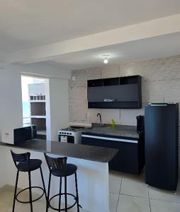 a kitchen with a counter and two bar stools at Apartamento Cantinho do Mar in Natal