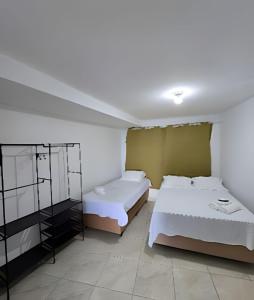 two beds in a room with white walls at Apartamento Cantinho do Mar in Natal