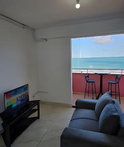 a living room with a couch and a flat screen tv at Apartamento Cantinho do Mar in Natal