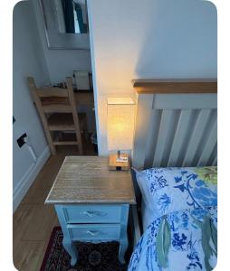 a bedroom with a bed and a table with a lamp at Shangri-La in Chesham