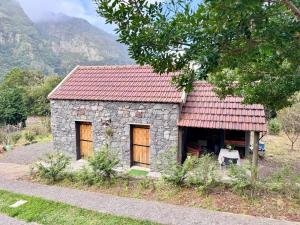 a small stone building with a red roof at Casa do Til in Porto Moniz