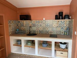 a shelf in a kitchen with a tiled wall at Maison dans le quartier de terre sainte Nicolas in Saint-Pierre +3 photos