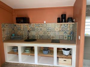 a kitchen shelf with a wall with tiles at Maison dans le quartier de terre sainte Nicolas in Saint-Pierre