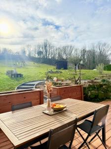 a wooden table with a bowl of fruit on a deck at La Chambrote - Maison, spa privatif & clim in Brive-la-Gaillarde +17 photos