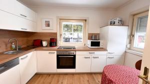 a kitchen with white cabinets and white appliances at Rosis Cottage in Lienz +20 photos