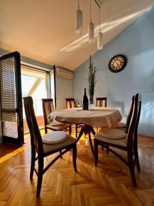 a dining room with a table and chairs and a clock at Apartment Magdalena in Dobrota