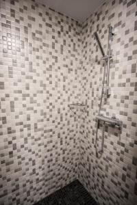 y baño con ducha en una pared de azulejos. en Apartamentos Mirador en Gúdar