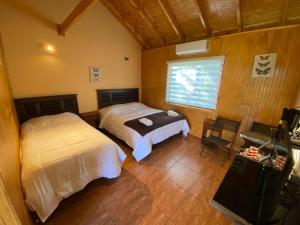 a bedroom with two beds and a television in it at Patagonia Bordelago Lodge in Puerto Ingeniero Ibáñez