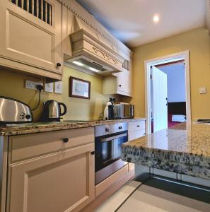 a kitchen with white cabinets and granite counter tops at Rowsley Cottage Bakewell Peak District in Bakewell
