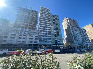 two tall buildings with cars parked in a parking lot at Oceano in Necochea