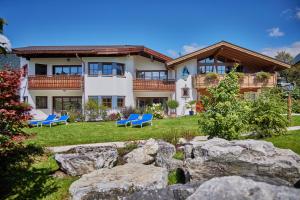 a large house with blue chairs in the yard at Föhrenhof Apartments in Farchant
