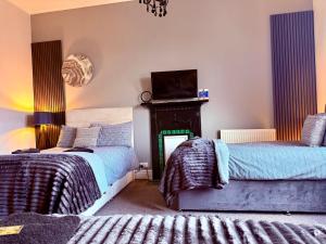 a bedroom with two beds and a fireplace at St Andrews house Hotel in Preston