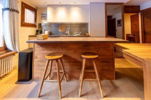 a kitchen with a wooden counter and two stools at Les Lauzes 32-46 in Mussillon