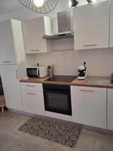 a kitchen with white cabinets and a black appliance at VILLA Papillon , maison entière avec jardin in Champigny-sur-Marne