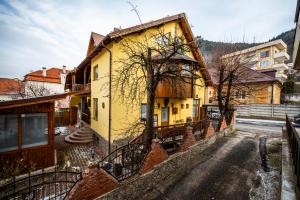 a yellow house on the side of a street at Pension Brasovu Vechi in Braşov
