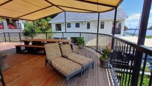 a deck with two chairs and a table and an umbrella at Harties Boathouse in Hartbeespoort