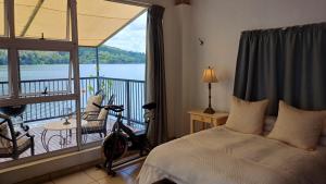 a bedroom with a bed and a balcony with a view at Harties Boathouse in Hartbeespoort