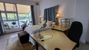 a bedroom with a bed and a desk with a lamp at Harties Boathouse in Hartbeespoort