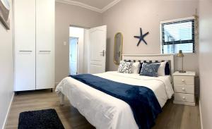 a bedroom with a large white bed and a mirror at Living Lite 1 and 2 in Kleinmond
