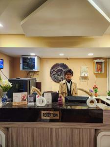 a man standing behind a counter in a restaurant at Arcadian Hotel in Gangtok