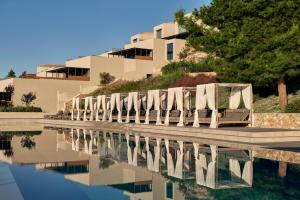 a row of white chairs sitting next to a pool at Celestial All Suites in Kefallonia